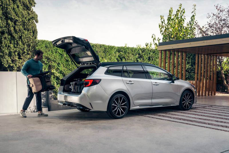 En man lastar in saker i bageutrymmet av en Toyota Corolla Touring Sports.